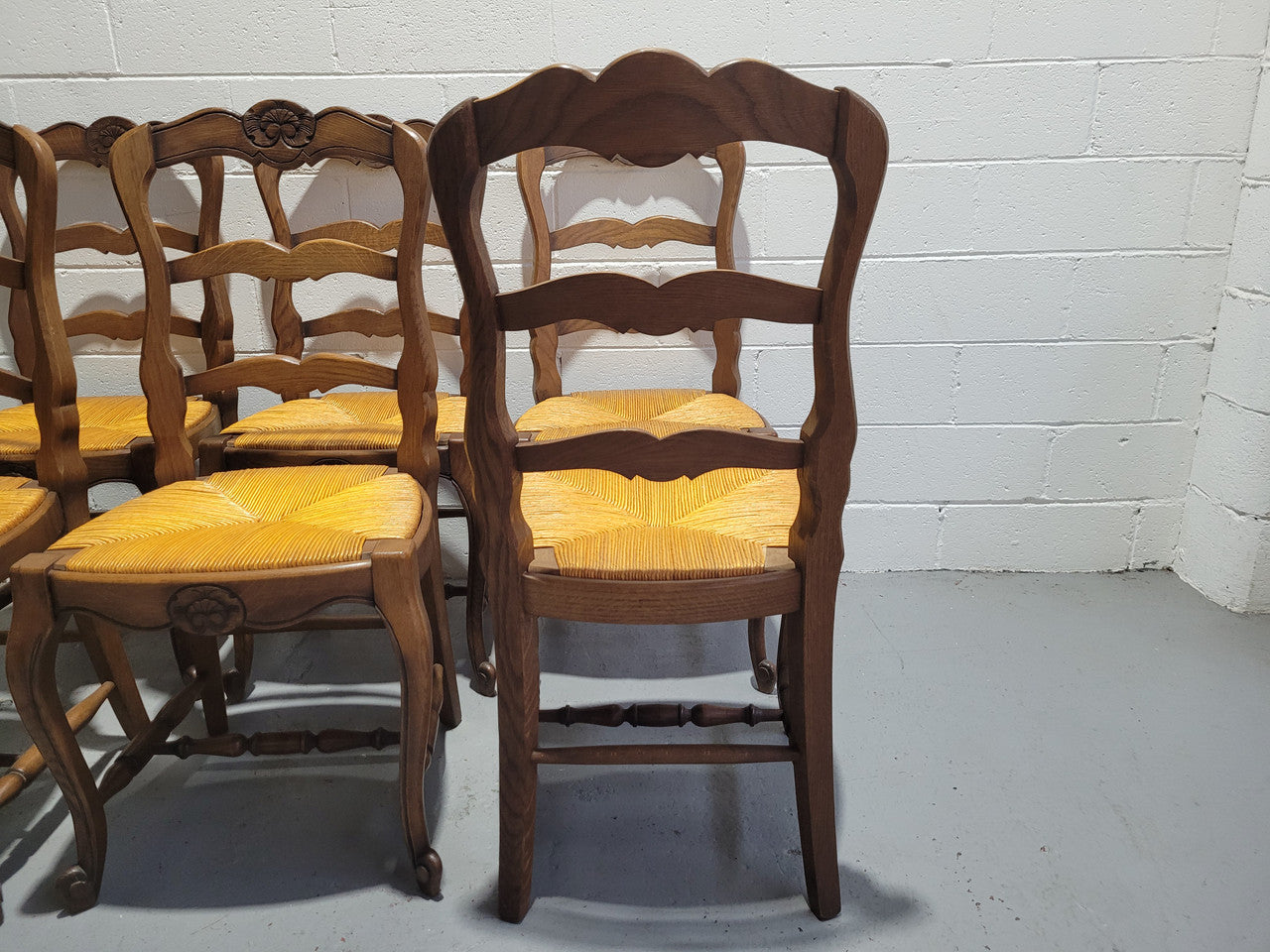 A set of 6 French Louis XV style oak dining chairs with rush seats in good original condition. All chairs have been detailed and re-glued where needed.