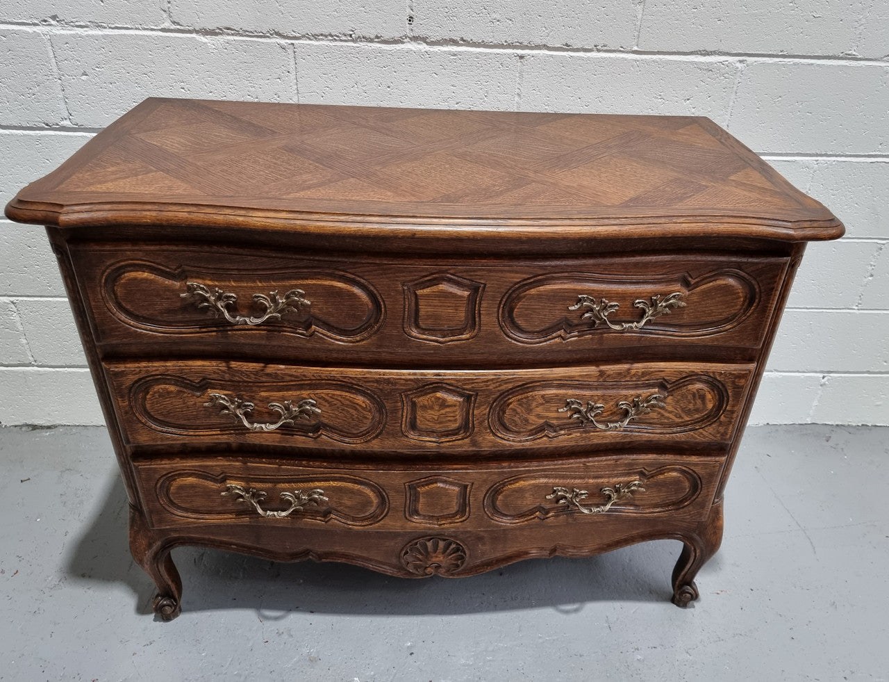 Lovely French nicely carved chest of 3 drawers with a parquetry top, with decorative handles and lovely carving. In good detailed condition.