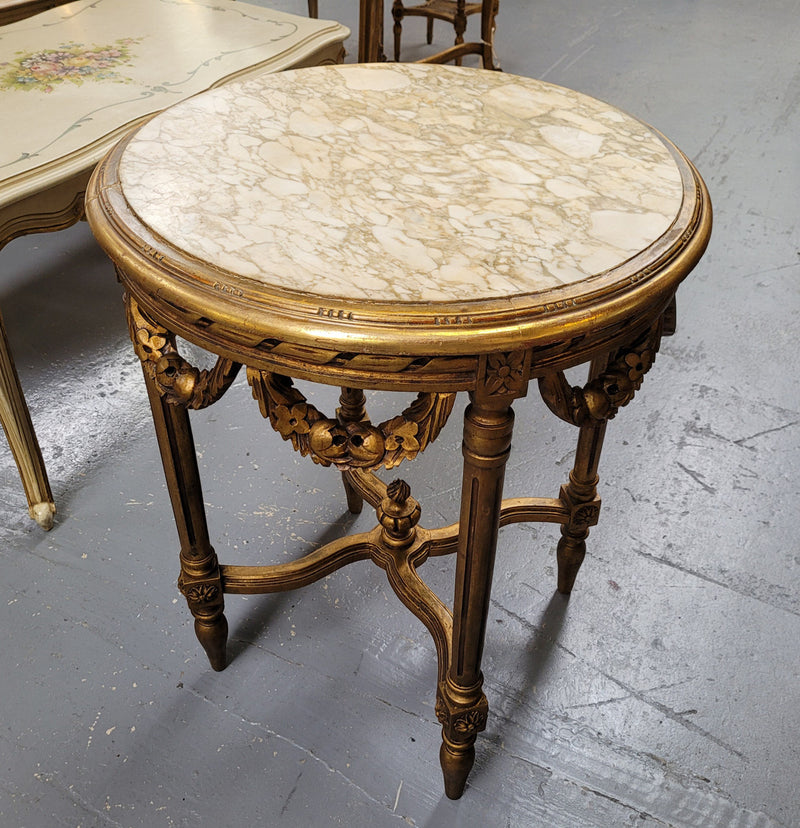 French Louis XVI style round marble topped gilded lamp/side table featuring lovely carved swags and undercarriage. It has been sourced from France and is in good original detailed condition.