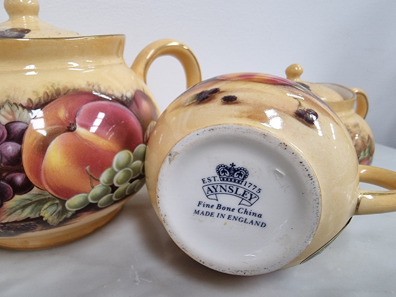 “Aynsley Orchard Gold” tea set on tray. Consisting of small teapot, lidded sugar and creamer. Please view photos as they help form part of the description.