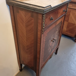 Louis 16th style marquetry inlaid side cabinet with a pierced brass gallery surrounding a marble top. It has two doors open up to storage with one shelf and a drawer above that. In good original detailed condition.