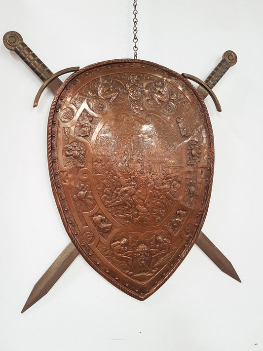 A beautiful European antique repousse copper shield, depicting a battle scene and with metal swords. It has been sourced from France and is in good original condition.