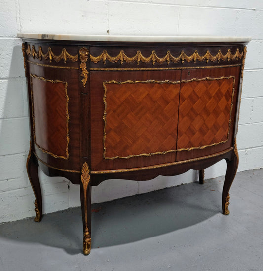 Vintage French style marble top two door half-moon buffet with beautiful decorative brass gilt mounts. In good original detailed condition.