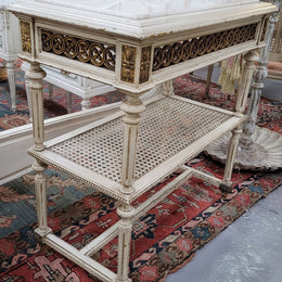 A fabulous painted French Louis XVI style white marble top console table. It has lovely carved detail with gilt highlights and a cane shelf. It has been sourced from France and is in good original condition.