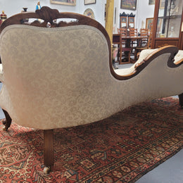 Upholstered Victorian walnut double ended chaise lounge with nice decorative carving. It has original castors and in very good condition. The upholstery is in "like new condition".