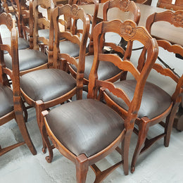 A set of ten French Louis XV style, ladder back oak chairs. With finely carved detail and newly upholstered leather look seat. In great original condition. Chairs are comfortable and sturdy for everyday use.