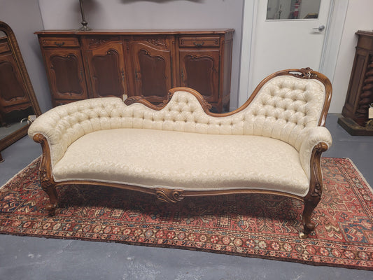 Upholstered Victorian walnut double ended chaise lounge with nice decorative carving. It has original castors and in very good condition. The upholstery is in "like new condition".