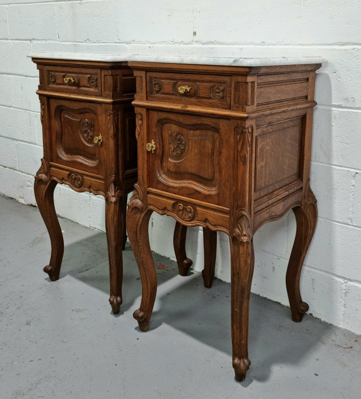 Beautiful pair of French Oak carved Louis XV style bedside cabinets with a white marble top, drawer and cupboard. They are in good original detailed condition.