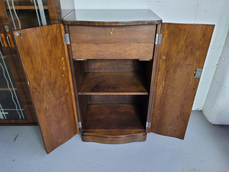 Art Deco Walnut display / drinks cabinet consisting of two glass door display and two door cupboard. Top section also lifts up and turns into a drinks area. All with original handles and in good original detailed condition.
