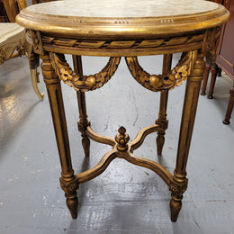 French Louis XVI style round marble topped gilded lamp/side table featuring lovely carved swags and undercarriage. It has been sourced from France and is in good original detailed condition.