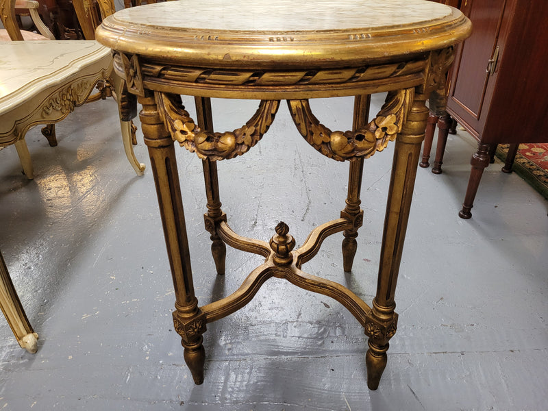 French Louis XVI style round marble topped gilded lamp/side table featuring lovely carved swags and undercarriage. It has been sourced from France and is in good original detailed condition.