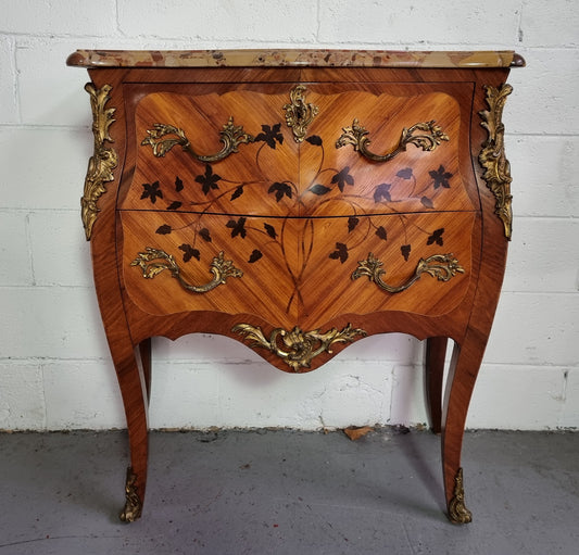 Charming petite French Louis XV style commode featuring two drawers, marquetry inlay, ormolu trim and marble Top. In good original detailed condition.  Circa: 1930’s.