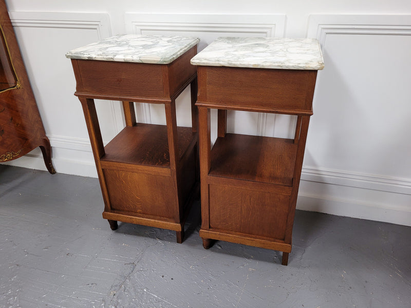 Pair of Antique French Oak Louis XVI style marble top bedside cabinets. They have decorative inlay and have been sourced from France. They are in good original detailed condition.