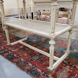 A fabulous painted French Louis XVI style white marble top console table. It has lovely carved detail with gilt highlights and a cane shelf. It has been sourced from France and is in good original condition.