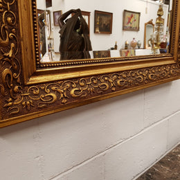 19th Century French Louis XV style gilt wall mirror with fabulous highly decorative crest at the top and a beveled edge mirror. In good original detailed condition.