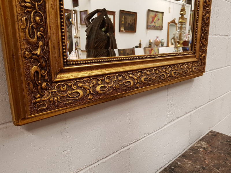 19th Century French Louis XV style gilt wall mirror with fabulous highly decorative crest at the top and a beveled edge mirror. In good original detailed condition.