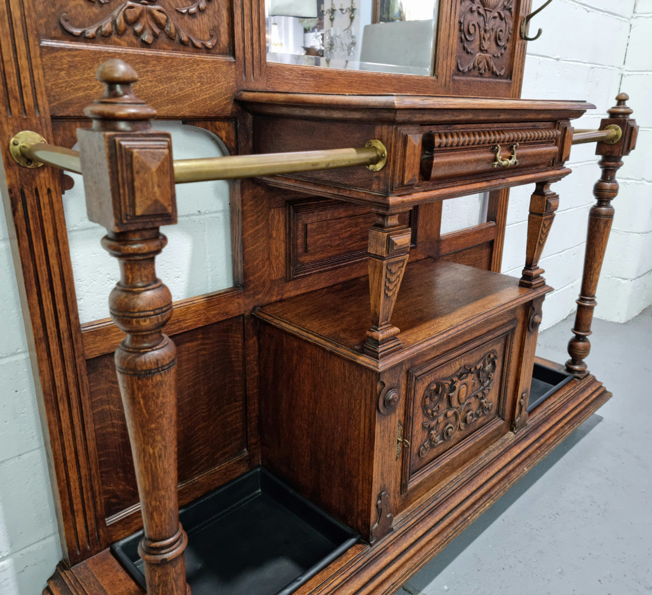 Grand Henry 2nd Style French Oak hall stand with 12 hanging hooks. Also has one cupboard and drawer for storage along with a mirror and two areas either side for umbrellas and walking sticks. In good original detailed condition.