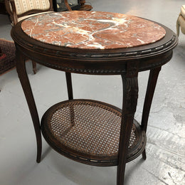 A charming 19th century French Louis XVI style fruitwood 2 tier oval side table.  With marble top, cane base and carved detail on surrounds and legs.