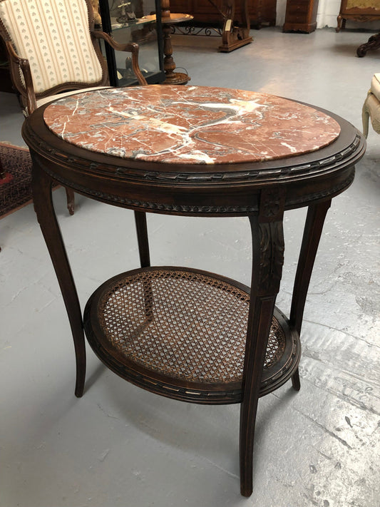 A charming 19th century French Louis XVI style fruitwood 2 tier oval side table.  With marble top, cane base and carved detail on surrounds and legs.