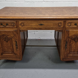 Fabulous French oak carved partners desk with a lovely parquetry top. It has three drawers and two cupboards on one side and two cupboards on the other side with no functioning drawers. It is in good original detailed condition.
