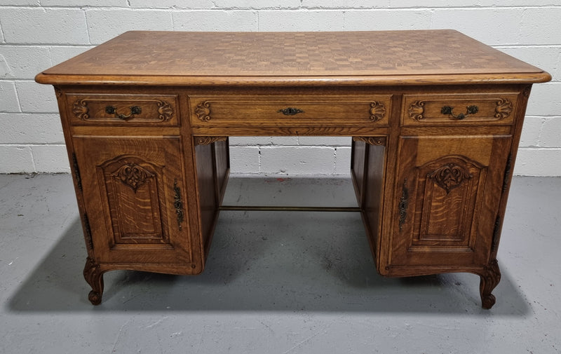 Fabulous French oak carved partners desk with a lovely parquetry top. It has three drawers and two cupboards on one side and two cupboards on the other side with no functioning drawers. It is in good original detailed condition.