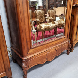 French Louis XV style Walnut armoire with single bevelled mirrored door. It has four adjustable shelves and a hidden exterior drawer at the bottom. It has been sourced from France and is in good original detailed condition.