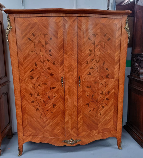 Charming French Louis XV Style Marquetry Inlaid Two Door Armoire. Features three adjustable shelves and ormolu trim. It has been sourced from France and is in good original condition.