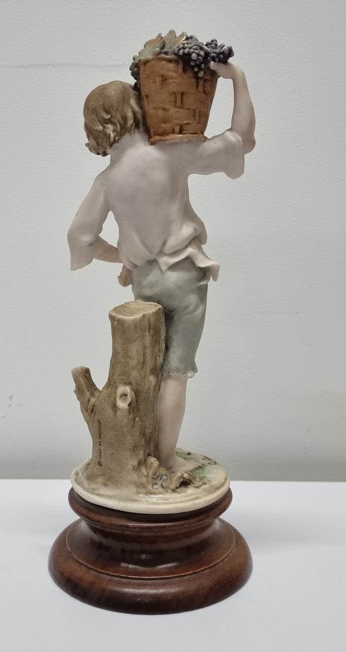 Lovely Italian figurine of boy carrying basket with grapes on a wooden base. It is signed Giuseppe Armani and 1982 FLORENCE. In good original condition.  Please view photos as they form part of the description.