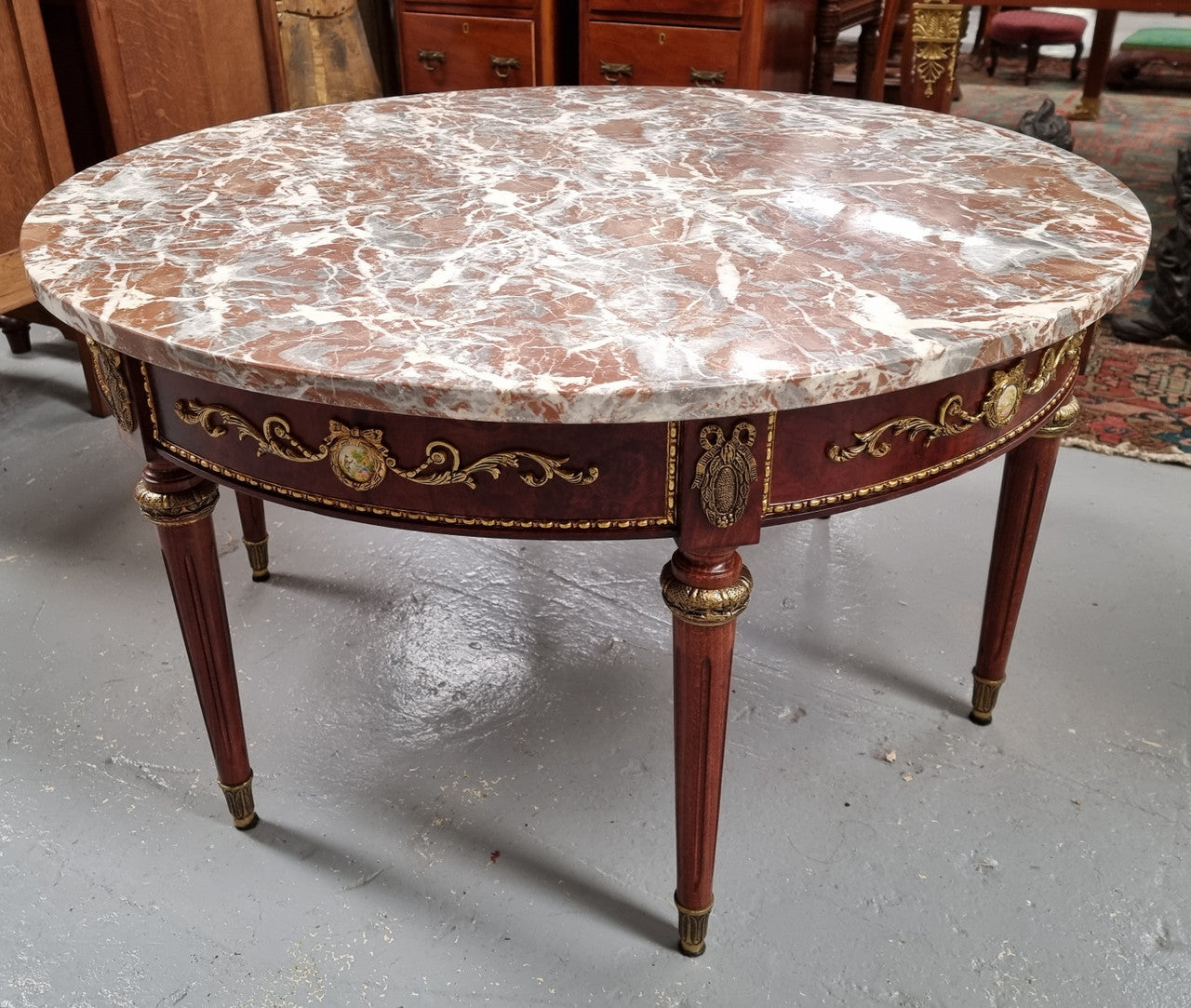 Stunning Antique French style Burr Walnut marble top coffee table. It has gilt metal mounts all around the top edge, with more down the fluted legs & feet. It also has exquisite painted porcelain plaques encased in gilt metal laurel wreaths all around the top edge. It is also stamped underneath "Muarva S.L. Made In Spain". It is in good original detailed condition.