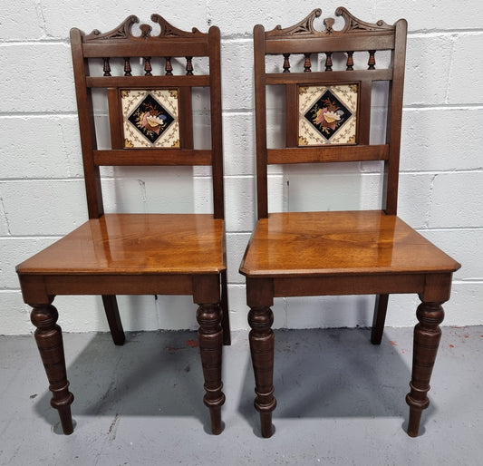 Pair of Edwardian Mahogany hall chairs with original tile in back. They are in very good original detailed condition.