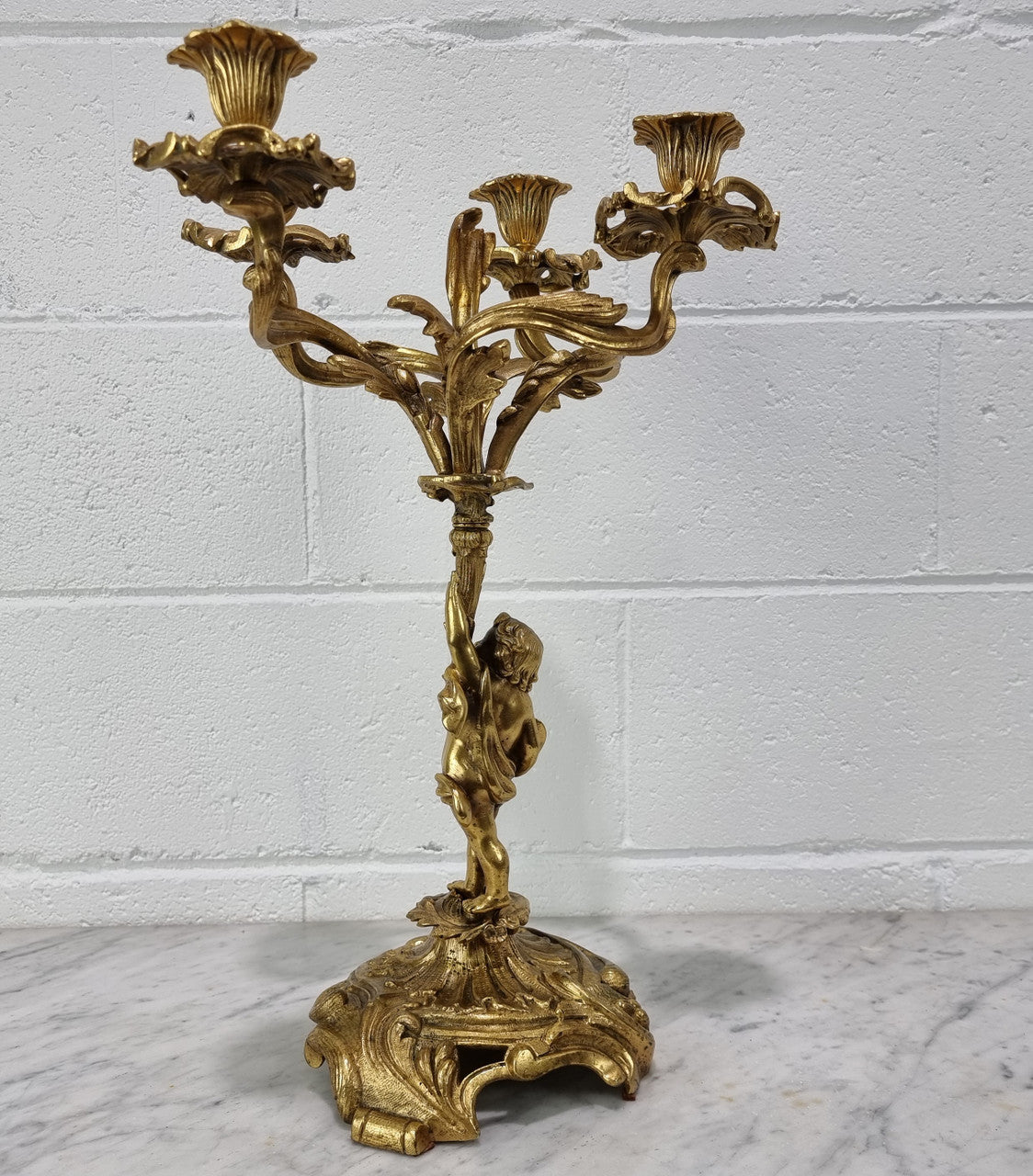 A pretty 19th Century French gilt bronze candelabra featuring a cherub. In good condition. Circa 1880.