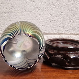 Iridescent glass egg shaped paper weight, on small wooden chinese stand. In good original condition. Please see photos as they form part of the description.