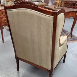 Beautifully carved Louis XVI Walnut upholstered wingback chair. The upholstery is in good original condition with no tears. The chair is also in very good original condition.