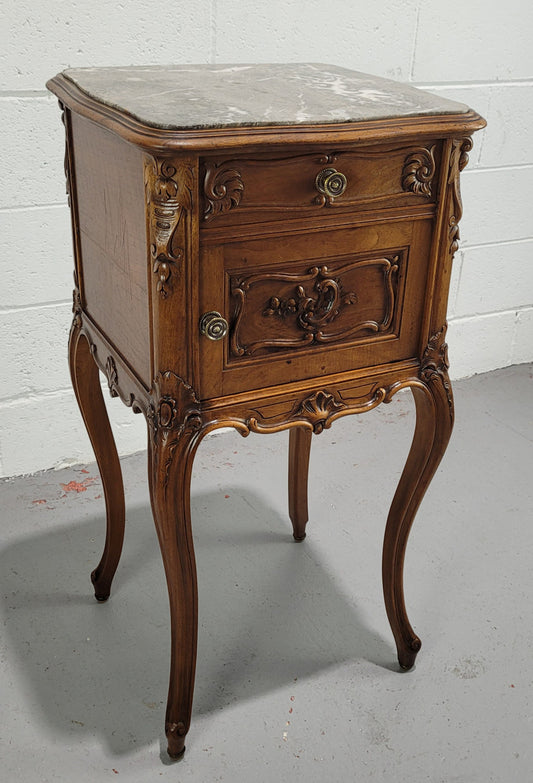 Beautiful French Walnut carved bedside cabinet with a lovely grey coloured inset marble top. The inside of the cupboard is also marble lined and it is in good original detailed condition.