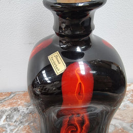Vintage Designer glass carafe by “Stromit Handarbeit”.  Dark background with flashes of orange/red.