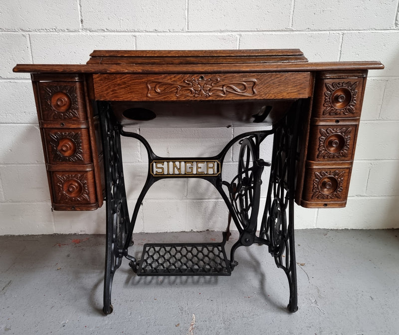 Singer Treadle sewing machine with six decorative side drawers and one centre drawer in Oak on cast iron base. It is in original condition.