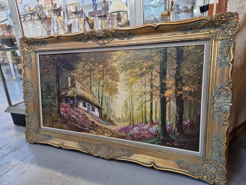 Vintage French oil painting on canvas in original gilt frame of "Forest Cottage Scene". Circa 1950's.