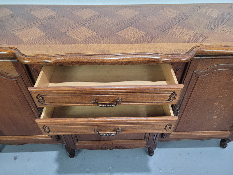 French Louis XV style parquetry top three door sideboard with two drawers. Plenty of storage space with a shelf behind each door. It is in good original detailed condition.