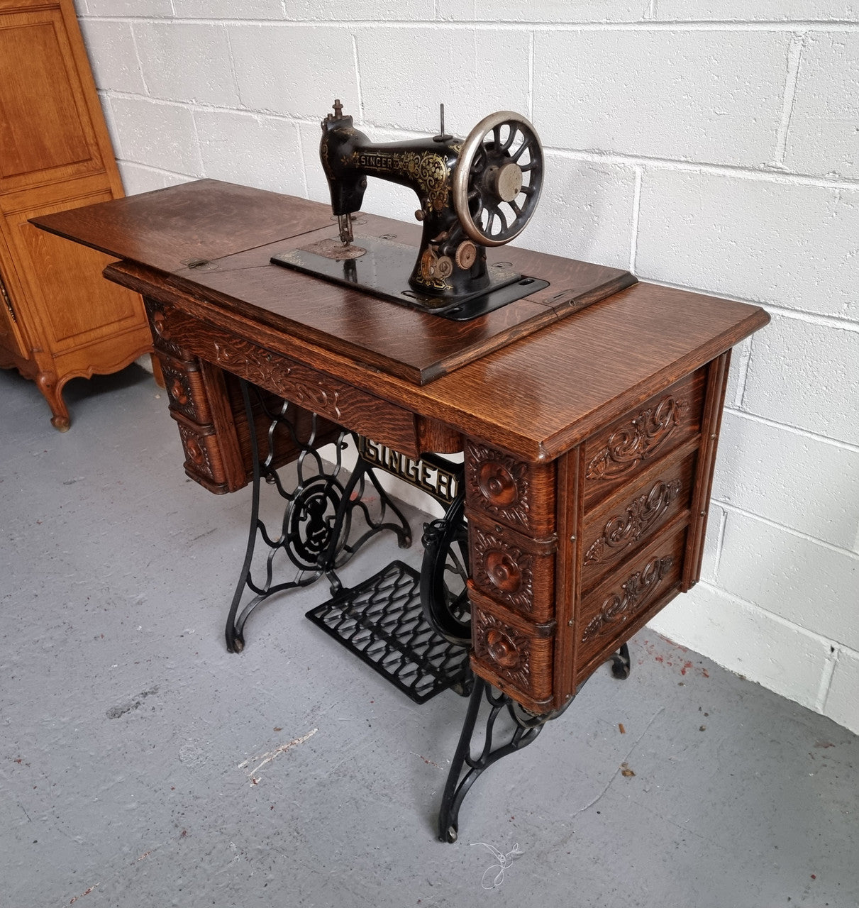 Singer Treadle sewing machine with six decorative side drawers and one centre drawer in Oak on cast iron base. It is in original condition.