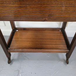 Oak drop leaf auto trolley on wheels. Both sides open up to make a larger table. It is in good original detailed condition.