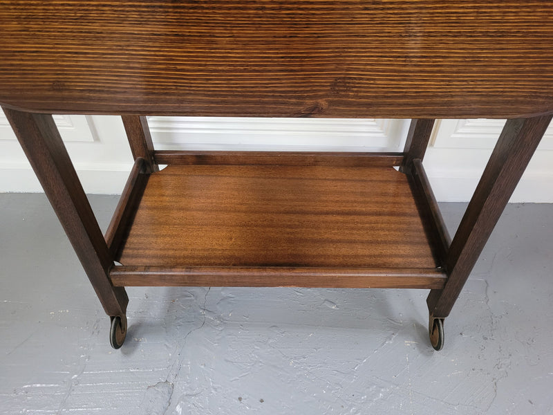 Oak drop leaf auto trolley on wheels. Both sides open up to make a larger table. It is in good original detailed condition.