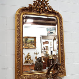 19th Century French Louis XV style gilt wall mirror with fabulous highly decorative crest at the top and a beveled edge mirror. In good original detailed condition.
