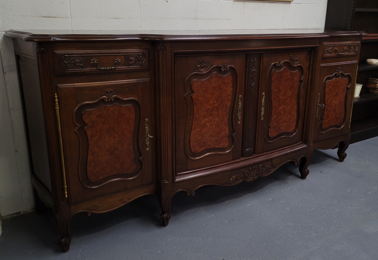 Fabulous Louis XV style French Walnut and Burr Walnut four door sideboard. Each door panel has beautiful Burr Walnut panels and open up to an adjustable shelf. Beautiful handles and two drawers for added storage. In good original detailed condition.