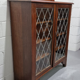 Lovely leadlight two door Oak bookcase/display cabinet with four wooden shelves. It is in good original detailed condition.