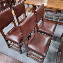 Set of eight Henry II style dining chairs including two carvers. They have leather look upholstery with brass studs. In good original condition.