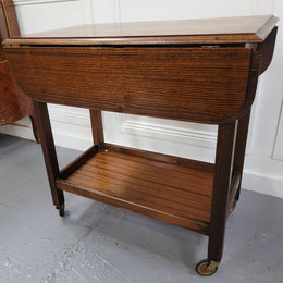 Oak drop leaf auto trolley on wheels. Both sides open up to make a larger table. It is in good original detailed condition.
