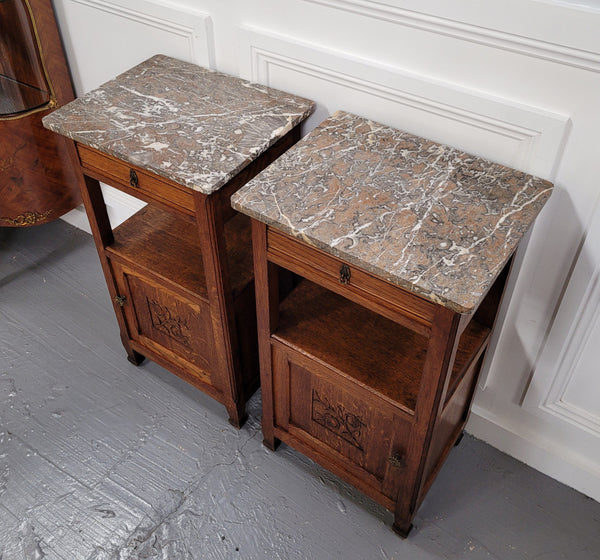 Pair of French Oak Arts & Crafts style marble top bedside cabinets. They have lovely carvings on the door, an open shelf in the middle and drawer at the top. They are in good original detailed condition.
