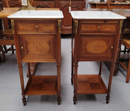 Pair of white marble topped Louis 16th style bedside cabinets consisting of one drawer and one cupboard.  Inlaid with burr walnut and has decorative mounts. They have been sourced from France and are in good original condition.