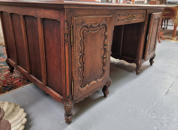 Fabulous Louis XV style French Oak beautifully carved full partners desk with an amazing tooled leather top. Both sides have a functioning drawer in the middle and two cupboards either side. On both sides one cupboard door opens up to four smaller internal drawers. Plenty of storage space and a large top surface to work on. It is in good original detailed condition.