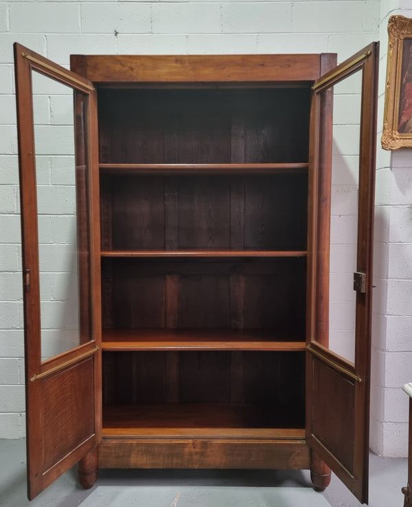 Grand French Mahogany Empire two door bookcase. It has beautiful glass doors and has three fully adjustable shelves. It has been sourced from France and is in good original detailed condition.